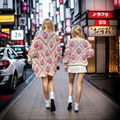 two women walking down a city street holding hands