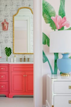 a bathroom with pink and blue cabinets, a large mirror and a painting on the wall