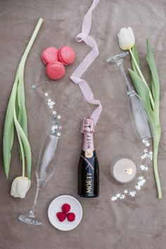 a bottle of champagne next to some flowers and other decorations on a table with wine glasses