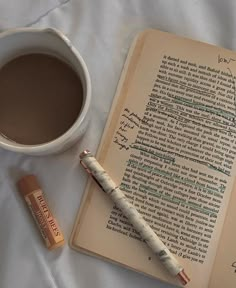 an open book with writing on it next to a cup of coffee and a pen