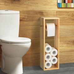 a toilet with two rolls of toilet paper in it next to a wooden holder for toilet paper