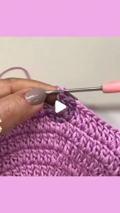 a woman is knitting with pink yarn and crochet needles