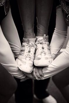 two people holding their hands together in front of each other with white sneakers on them