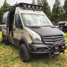 a mercedes benz camper van parked in the grass with its doors open and lights on