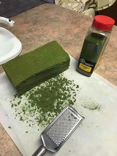 a grater next to a green cake on a counter