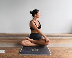 a woman is sitting on a yoga mat and meditating