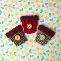 three small crocheted cups sitting on top of a flowered table cloth covered surface