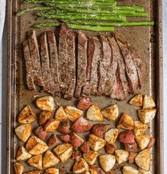 steak, potatoes and asparagus on a baking sheet