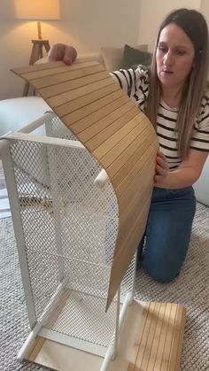 a woman sitting on the floor next to a doll house that is made out of cardboard