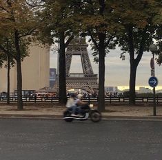 a person riding a motorcycle down the street in front of the eiffel tower