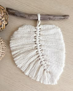 a white piece of cloth with tassels next to a wicker basket and driftwood