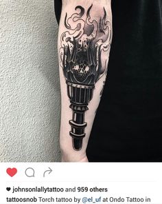 a person with a tattoo on their arm holding up a black and white ink torch