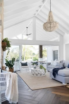 a living room filled with furniture and a chandelier hanging from the ceiling over a wooden floor