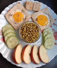 an assortment of food on a paper plate with bread, apples, and eggs in the middle