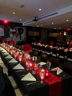 a long table is set with red and black linens for an elegant dinner party