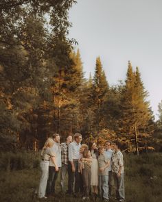 a group of people standing next to each other in a field with trees behind them