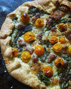 an uncooked pizza with tomatoes and other toppings sitting on top of a table