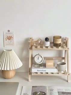 a table with books, magazines and a lamp on it in front of a white wall