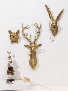 three gold deer head mounted to the side of a wall next to an empty bottle