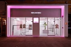 a store front with pink lighting and clothes on display