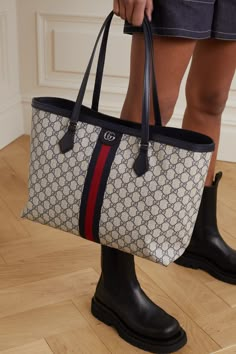 Combining three of Gucci's unmistakable signatures - the interlocking 'GG's, the 'Supreme' motif and the striped webbing - this 'Ophidia' tote is perfect for fans of the label's maximalist approach. It's made from durable coated-canvas with sturdy leather trims and a single zipped pocket inside. The interior is roomy enough for the busiest day. Gucci Tote Bag Outfit, Chanel Luggage, Gucci Bag Outfit, Gucci Ophidia Bag, New Gucci Bags, Gucci Handbags Outlet, Gucci Clothing, Luxury Tote Bags, Handbags Large