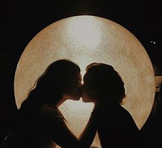 two people are kissing in front of a full moon