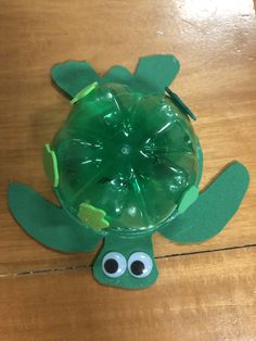 a turtle made out of plastic bottle sitting on top of a wooden table