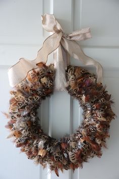 a wreath hanging on the front door with a bow around it's neck and feathers