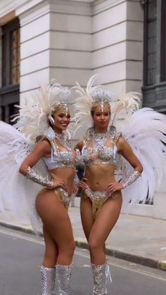 two women dressed in silver and white posing for the camera with angel wings on their bodies