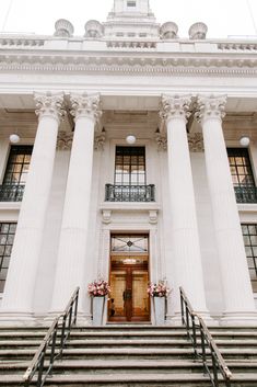 an old building with columns and flowers on the steps