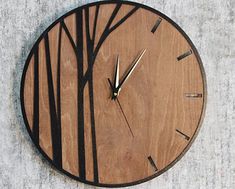 a wooden clock with trees on it sitting on the ground in front of a concrete wall