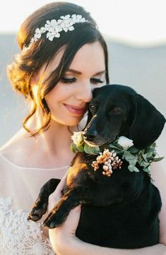 a woman in a wedding dress holding a black dog