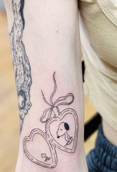 a woman with a tattoo on her arm holding a heart shaped locke and a dog inside it