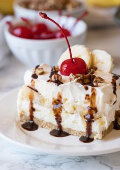 a piece of cake on a plate with chocolate sauce and cherries