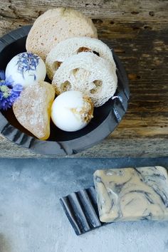 an assortment of food items in a bowl on top of a wooden table next to a slice of bread