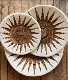 two woven baskets sitting on top of a wooden table next to each other with brown and white designs