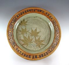 a ceramic bowl with leaves painted on the side and words written in black ink above it