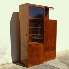 a wooden cabinet sitting on the side of a building next to a wall with a glass door