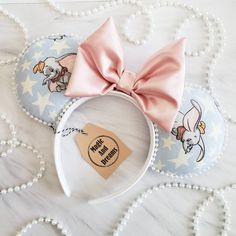 a minnie mouse ears with a pink bow on the top and an ear tag attached to it