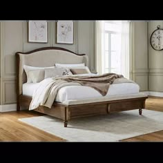 a large bed sitting on top of a hard wood floor next to a wall mounted clock