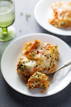 a white plate topped with lasagna casserole covered in cheese and spinach