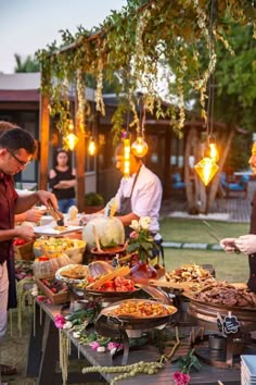 a group of people standing around a table filled with food