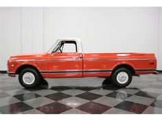 an orange truck parked on top of a black and white checkered floor