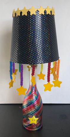 a colorful lamp with stars hanging from it's base and a black shade on top