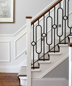 a white staircase with black iron railing and wood handrail