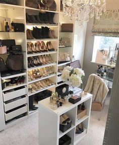 a room filled with lots of shoes and purses on shelves next to a chandelier