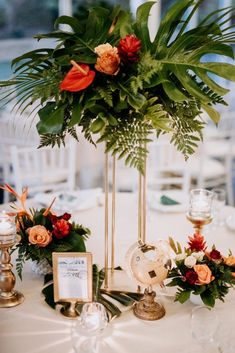 an arrangement of flowers and greenery is displayed on a table at a wedding reception