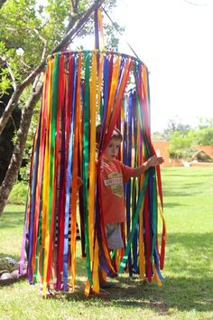 a young boy standing in front of a pole with streamers on it's sides