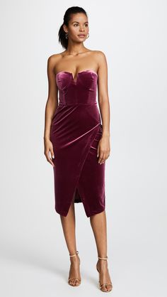 a woman wearing a purple velvet dress with an asymmetrical skirt and strapless top