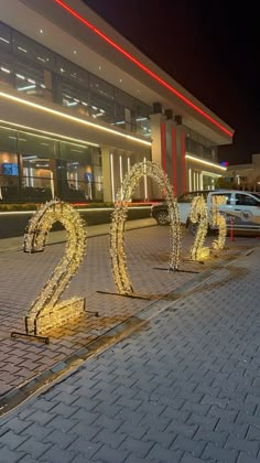 the numbers are lit up in front of a building with cars parked on the street